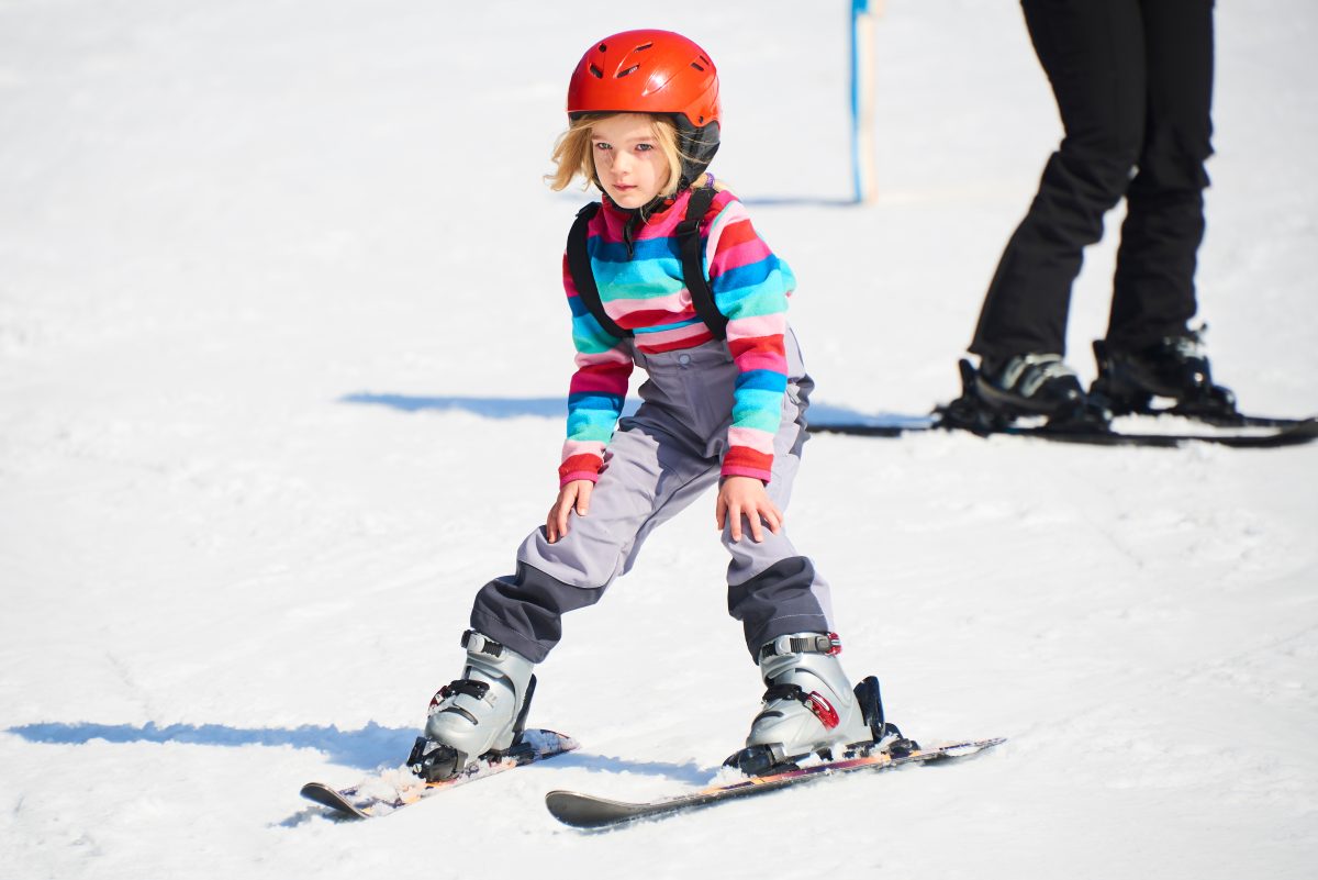 Child girl skiing in mountains. Active kid with safety helmet and goggles. 