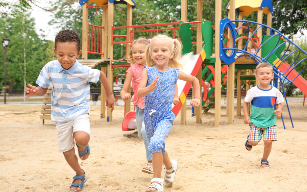 Group of young children running on a playground.